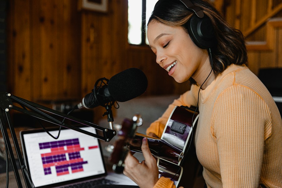 A musician in headphones singing into a microphone while playing guitar